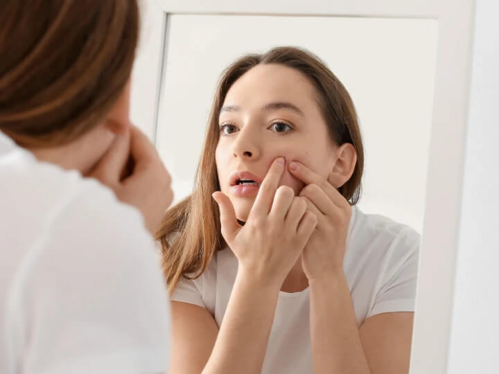 鏡で顔の肌状態を確認する女性